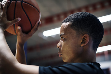 African American teenage boy concentrated on playing basketball