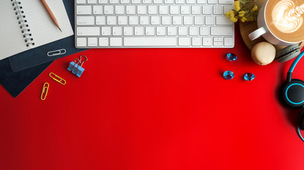 Styled stock photography red office desk table with blank notebook, keyboard, macaroon, supplies and coffee cup. Top view with copy space. Flat lay.