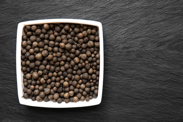 Close Up Fragrant Peppers in White Plate on Black Stone background Surface with Free Space