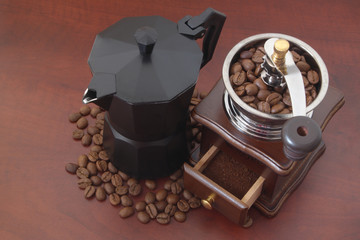 Moka coffee pot, old manual coffee grinder and roasted coffee beans on wooden table