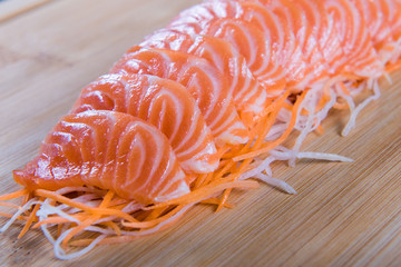 Salmon sashimi slice on carrot and radish wooden background. Japanese Food.