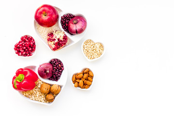 Diet for healthy heart. Food with antioxidants. Vegetables, fruits, nuts in heart shaped bowl on white background top view copy space