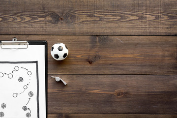 Sport coach concept. Pad with tactic plan of the match near whistle and football ball on wooden...