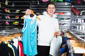 Sporty male is choosing new T-shirt for tennis in the store.