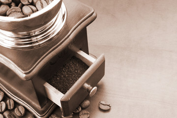 Vintage wooden coffee grinder with coffee beans on table with room for text