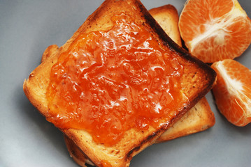 Fresh Toasts with Homemade Orange Jam on Gray Plate over Wooden Background.