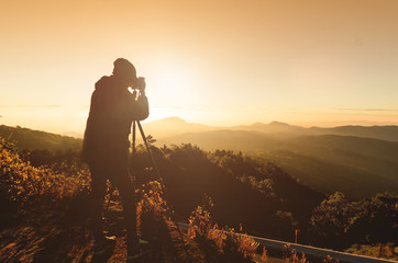 silhouette of photographer on top of mountain at sunrise background(vintage style)