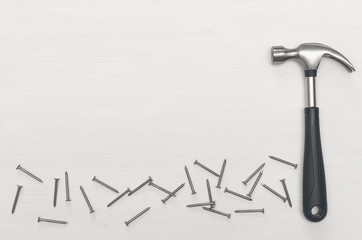 Hummer and nails on white wooden board surface background with copy space. Construction concept background.