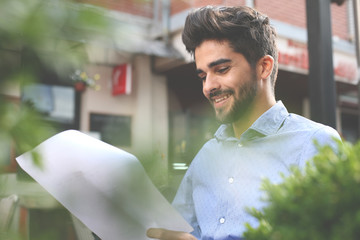 Smiling businessman reading document.
