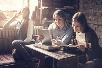 Happy smiling girls in library sitting together and studying.