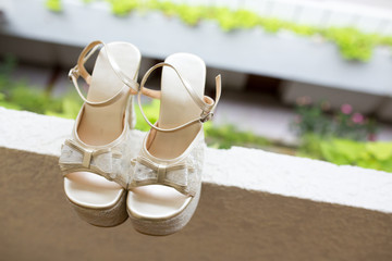 Beautiful white wedding shiny bride shoes outdoors at tree. Wedding morning preparation.