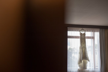 Fototapeta na wymiar Wedding dress of bride in daylight hanging on window