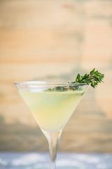 Tasty bitter cocktail with thyme in martini glass. Selective focus.