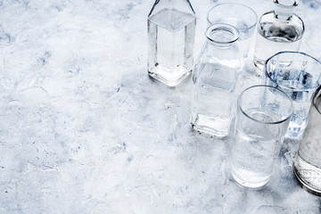 Drinking water in bottles and glasses on grey background copy space