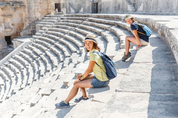 Two young girls student traveler in the ancient amphitheater. archaelolgy travel concept