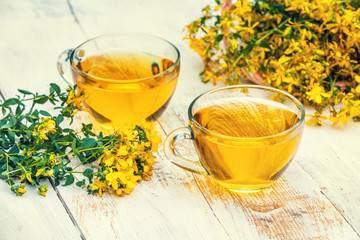 Two cups of Hypericum herbal (Tutsan) tea on wooden grunge table