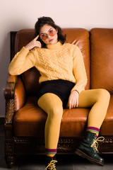 An attractive young girl sits on a beautiful leather sofa