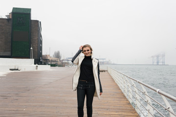 Young blonde is leaning on the door is standing on the waterfront.