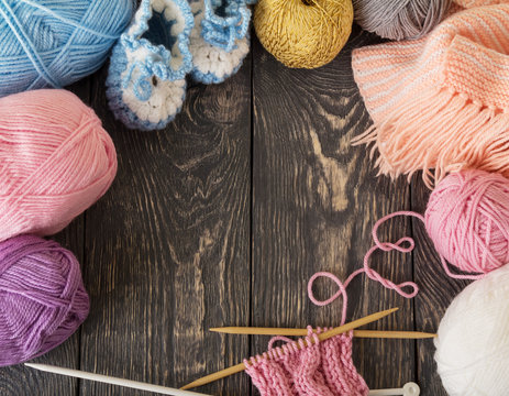 Colorful skeins of yarn and knitted products are handmade on wooden surface