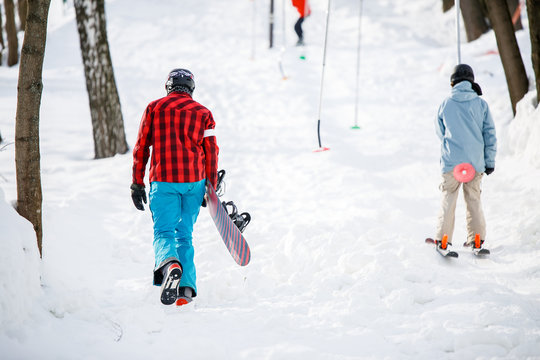 Photo of walking snowboarders from back in winter park