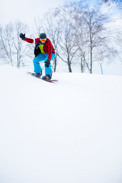 Image of sportsman in helmet with snowboard riding in snowy resort