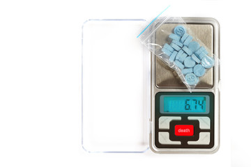 Pills of MDMA synthetic drugs on small digital scale