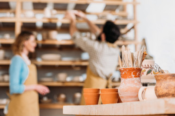 selective focus of potters in workshop with ceramic dishware on foreground