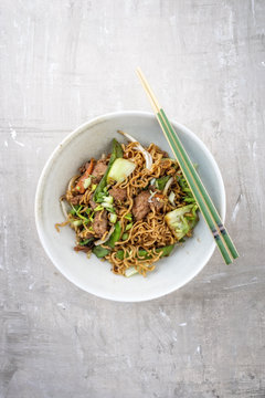 Traditional stir-fried Thai phat mama mie noodles with pork and vegetables as top view in a bowl with copy space