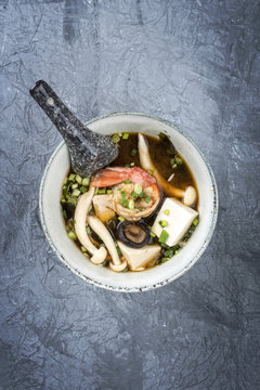 Traditional Japanese miso soup with king prawns and tofu as top view in a bowl with copy space