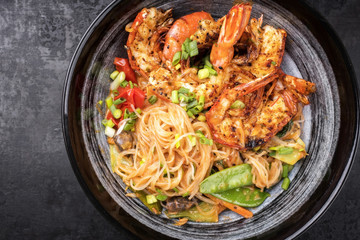 Traditional Thai Phak Kung curry with barbecue king prawns and noodles as top view in a bowl