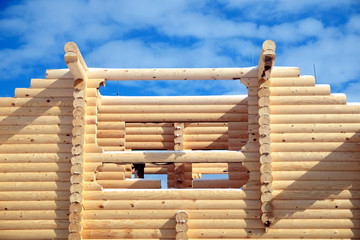 Facade of big rural house construction from sandy brown smooth planed heady pine logs on bright sunny winter day