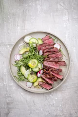 Poster Traditional barbecue skirt steak sliced with salad and avocado as close-up on a plate with copy space © HLPhoto