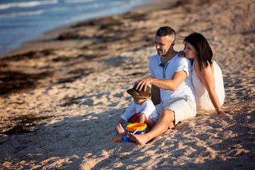 Young happy family sitting on the beach