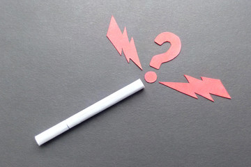 Cigarette on a black background, signs made of paper red and lightning question whether Smoking