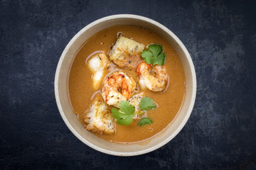 Traditional French fish soup with prawns and croutons at top view in a bowl
