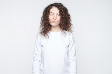 Puzzled shocked young female looks with bugged eyes at camera, being surprised to see big sales,...