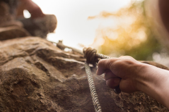 men climbing on rock outdoor, close-up image of climber hand