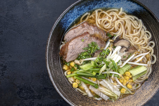 Traditional Japanese shoyu ramen with chashu as top view in a bowl with copy space left