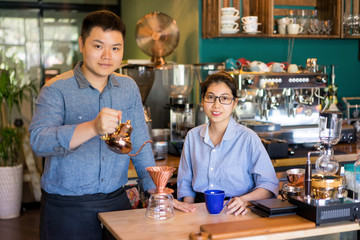 Modern Asian couple making best coffee in town. Content confident young family running own business. Coffee roasting house concept