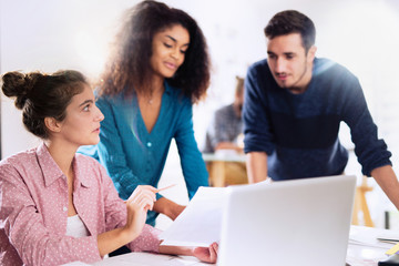 At office. A young multi-ethnic work team exchanges ideas ar