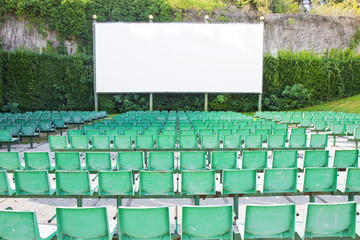 Outdoor cinema with chairs and white projection screen - obrazy, fototapety, plakaty