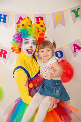 clown girl on the birthday of a child. A party for a child. Keep the baby in your arms