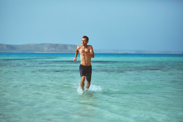 strong athletic man runs on the beach along the sea front. vacation and travel photography concept
