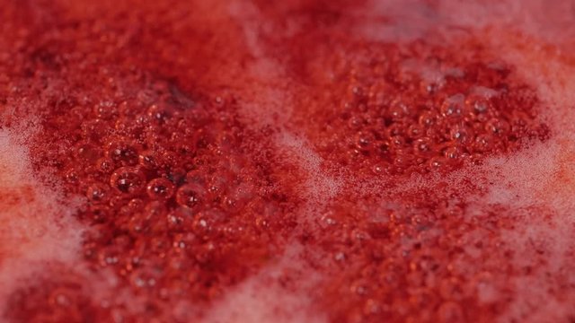 Close up of red cranberries boiling process in the boiler for jam. Macro shot.