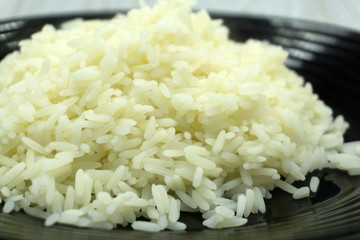 Basmati rice in small wooden bowls and spoon on black wooden background close-up .