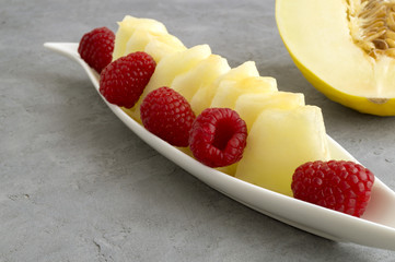 Summer fresh snack, melon and raspberry in a glass bowl.