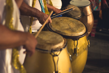Group of men playing yellow drums at carnival parade at night. Brazil batucada musicians. Party...