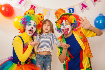 clown girl and clown boy at the birthday of a child. Party for children. Clowns and little girl show different emotions