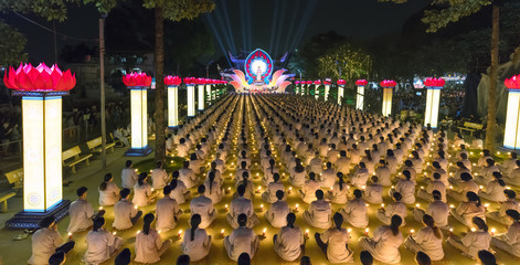 Ho Chi Minh City, Vietnam - January 3, 2018: Buddhists pray Buddha Amitabha chickened oriented festival stage with flickering candles illuminates halo radiating toward the night in Ho Chi Minh, Vienam