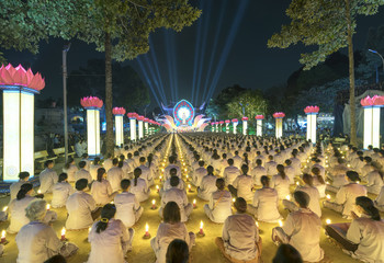 Ho Chi Minh City, Vietnam - January 3, 2018: Buddhists pray Buddha Amitabha chickened oriented festival stage with flickering candles illuminates halo radiating toward the night in Ho Chi Minh, Vienam